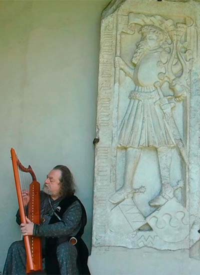 Beim Gedenkstein von Oswald von Wolkenstein als Kreuzritter (vermutlich um 1408), im westlichen Arkadengang des Domes von Brixen, mit gotischer Memling-Harfe, 30. Mai 2018